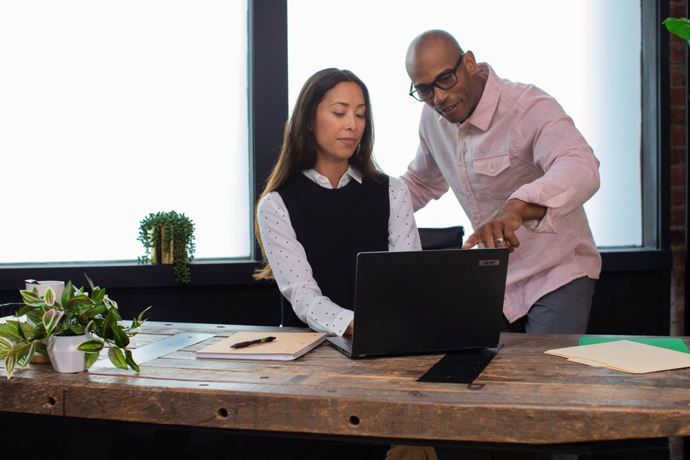 woman and man collaborating in windows at desk on a laptop