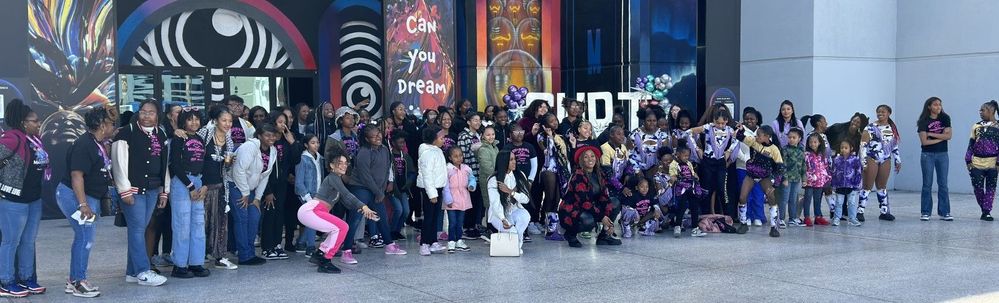 A group of students and adults stand together in front of a banner reading, “Can you dream?"