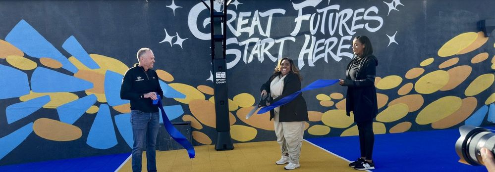 A group of three people performing a ribbon cutting ceremony.