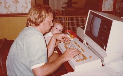 Seth Fewell as a baby sits next to his dad, who is working on an early computer