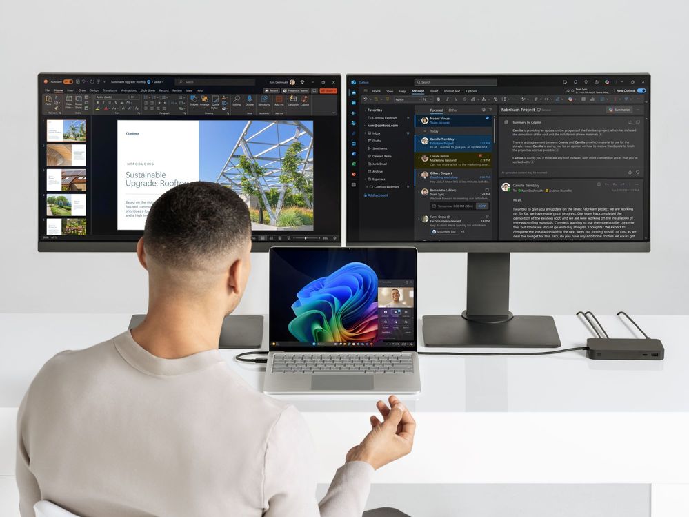 Photograph of male collaborating on a Copilot+ PC Surface Laptop with bloom with 2 monitors