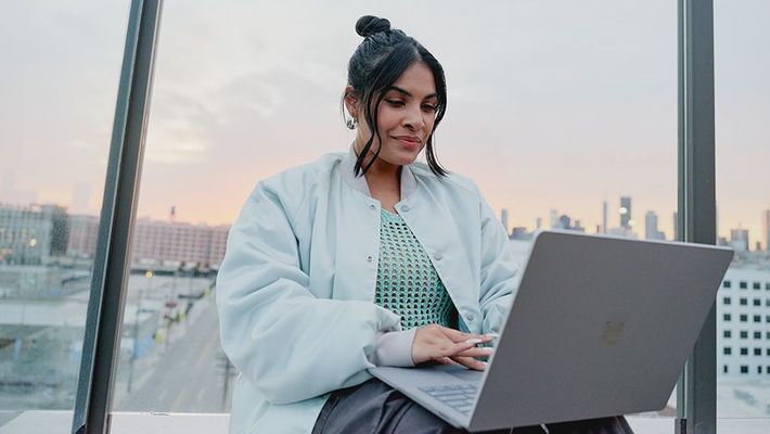 seated woman wearing a coat while working on a laptop on a rooptop.jpg