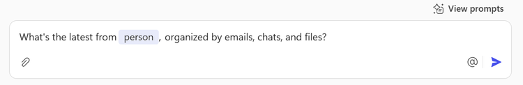 A screen capture of a sample Microsoft-provided prompt that reads, “What’s the latest from [person], organized by emails, chats, and files?”