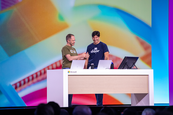 Two men looking at three Windows devices on stage