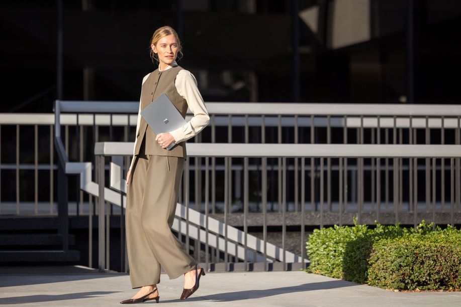 Woman holding Surface device walking in front of a staircase