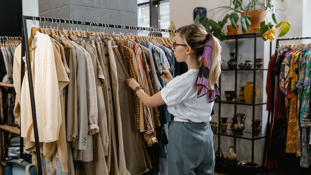 A retail employee organizes clothes on a display rack.