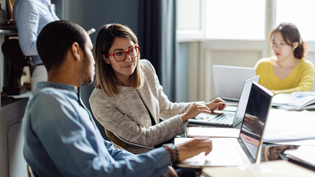 Two people at their lap tops collaborating