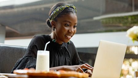 woman working on a laptop at an outdoor cafe