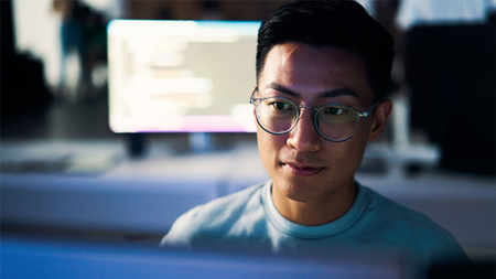 Photo: Man looks at a monitor with another monitor behind him