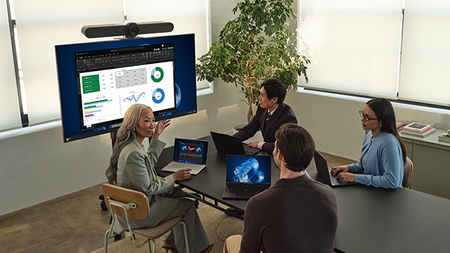 Four office workers sitting together at a table with their laptops