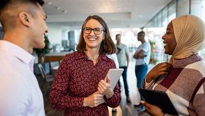 Business colleagues discuss work while holding notebooks and tablets