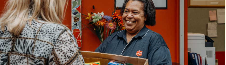Salvation Army employee smiling at a person while holding a box