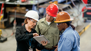 Woman using a tablet in discussion with two other colleagues on a job site.