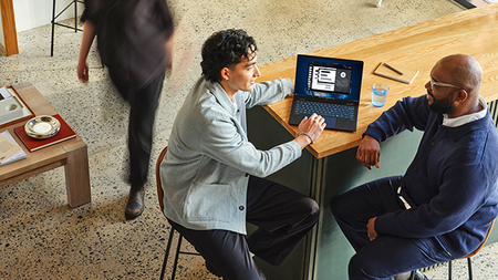 Two people sitting at a table at work talking