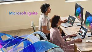 Two professionals sitting at a desk with laptops and monitors