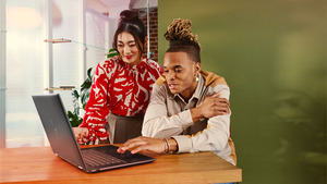 Woman (standing) and man (seated) in consultation in front of a laptop.