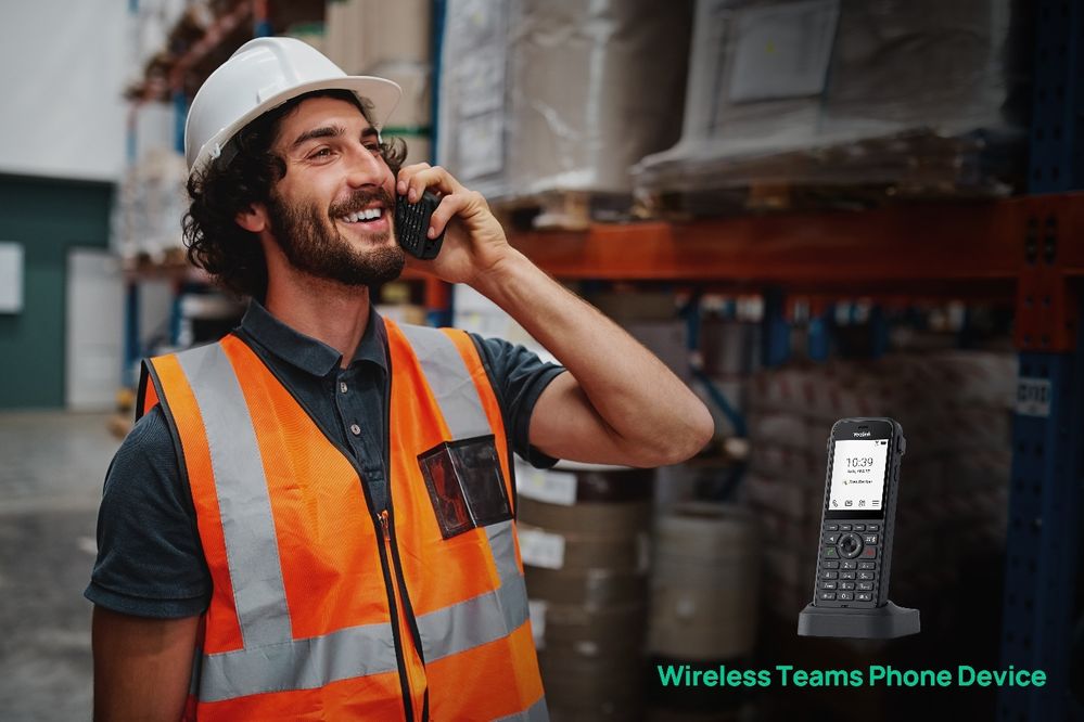 A man in a hard hat and high visibility vest uses a portable phone in a warehouse. An inset picture shows the Yealink MP66W Wi-Fi based Teams Phone Device.