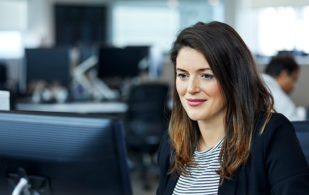 Smiling businesswoman using a computer sitting at a desk in an office