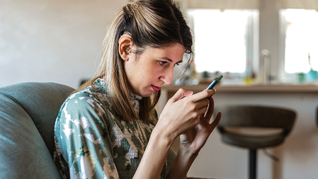 Woman with hearing aids and vision impairment uses a smartphone in her living room