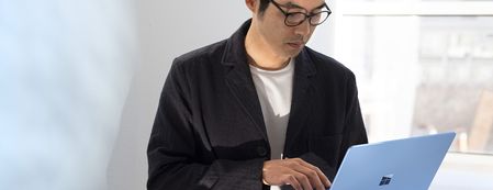 Adult male standing in an office using a Surface Laptop