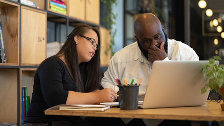 Business partners working on a laptop at a table in a modern office