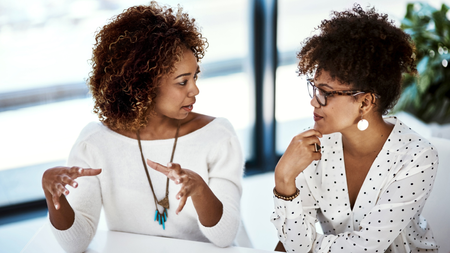 Two professionals working in a modern office discuss something of great interest