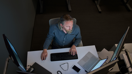 IT admin sits at a desk with multiple monitors analyzing data
