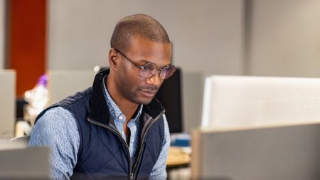 An IT admin engages in focused work in an open office environment.