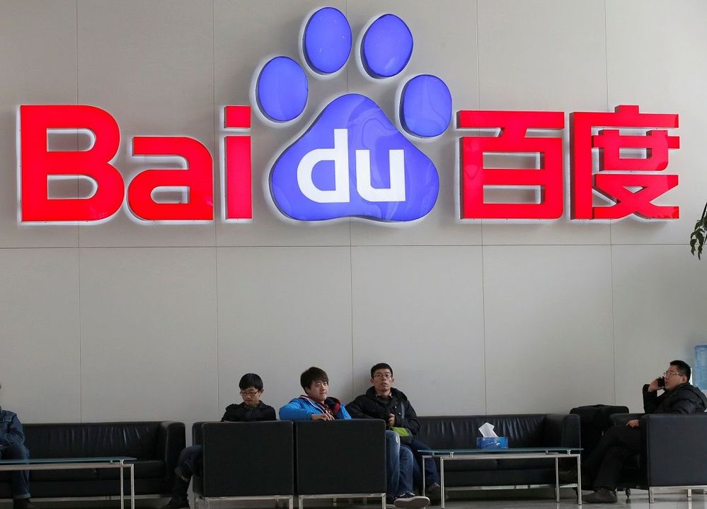 People sit in front of the company logo of Baidu at its headquarters in Beijing.